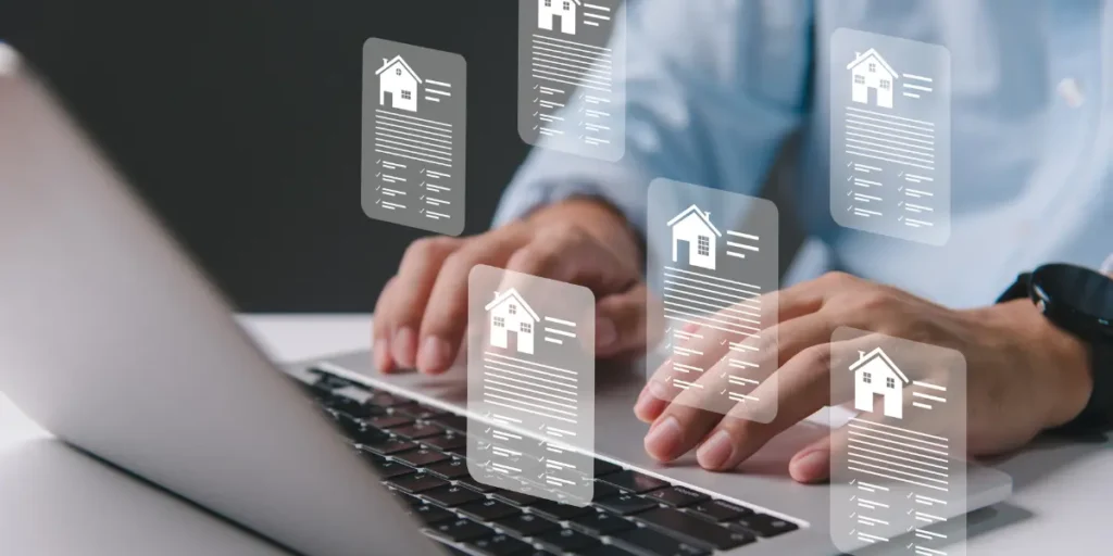 Lançamentos imobiliários: Lançamentos imobiliários: Uma imagem mostra as mãos de uma pessoa digitando em um laptop, com vários ícones de casas e documentos transparentes sobrepostos na tela.