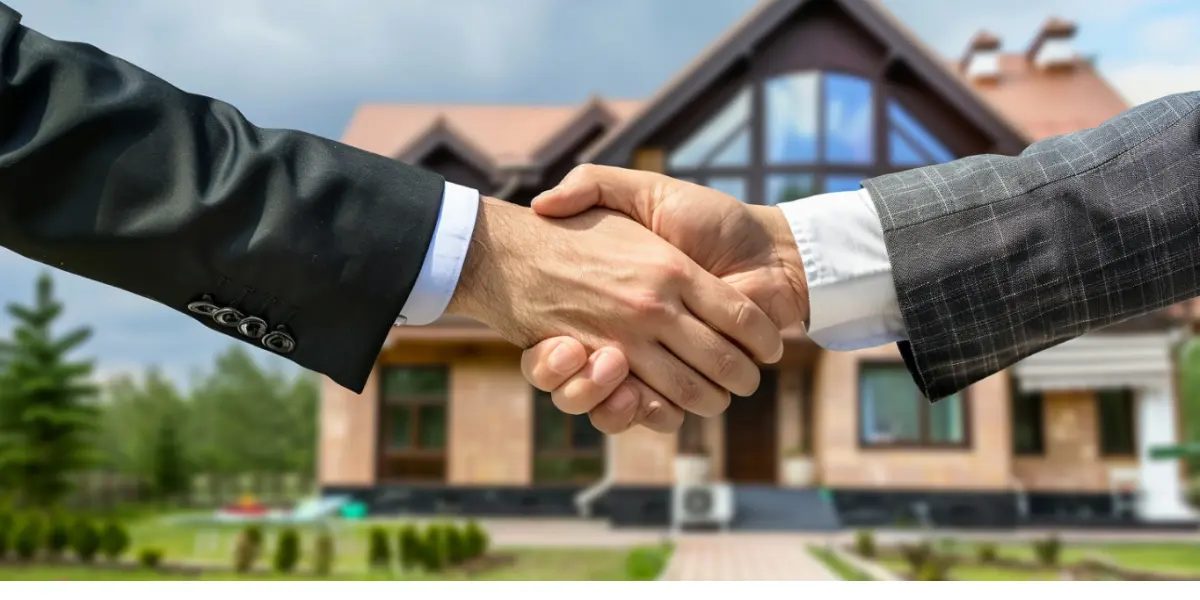 Parcerias imobiliárias: Duas pessoas estão a dar as mãos em frente a uma casa, simbolizando um acordo ou transação.
