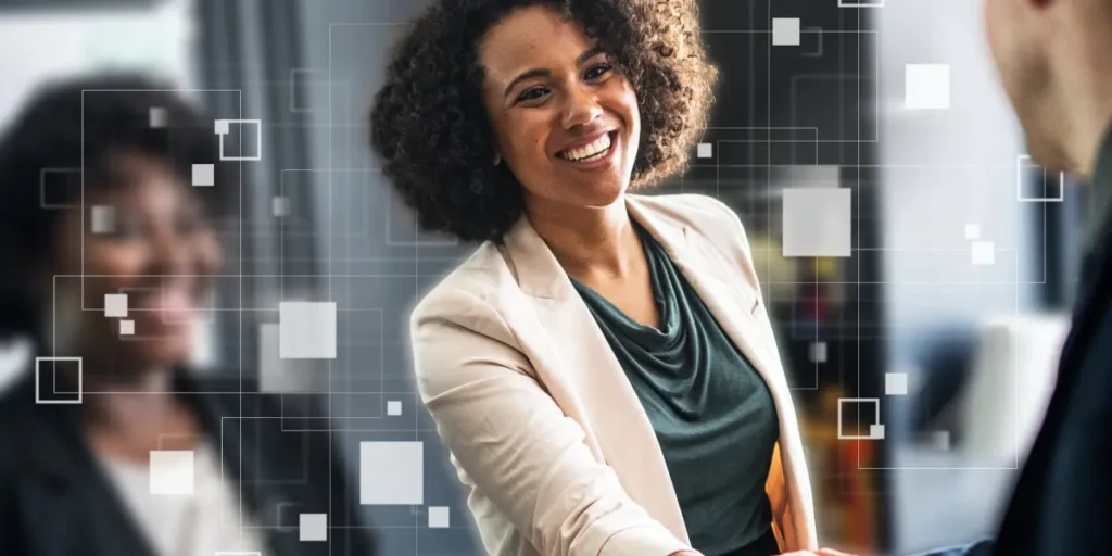 Qualificação de leads imobiliários: A cena é composta com um foco claro em uma mulher, que está no centro da imagem, e um homem que se encontra parcialmente fora do enquadramento, ambos apertando as mãos. Ao fundo há uma segunda mulher, com a imagem desfocada, sorrindo. Há presença de elementos gráficos abstratos no fundo da imagem.