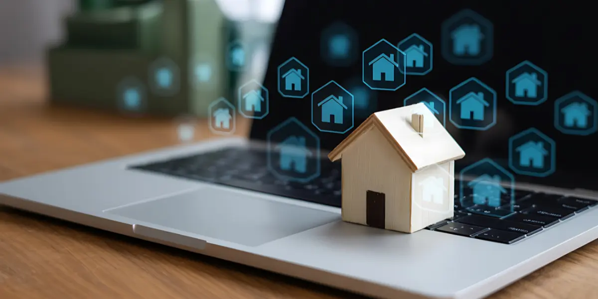 Como funciona a plataforma de imóveis Avendre: imagem mostra um notebook em cima de uma mesa, aberto. Em cima do teclado há a miniatura de uma casa feita em madeira, e da tela saem ícones em 3D de casas.